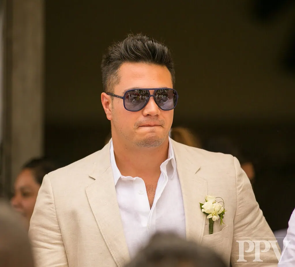 Hombre con gafas de sol y traje beige en evento formal, promoviendo soluciones tecnológicas y de inteligencia artificial para empresas.